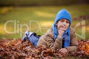Smiling boy with hand on chin in park during autumn