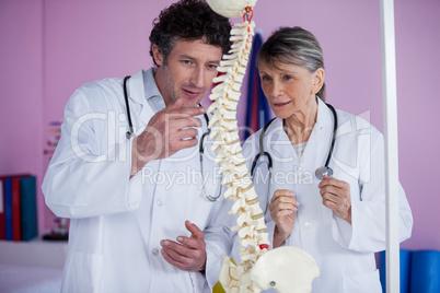 Two physiotherapists discussing with spine model