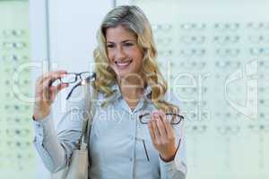 Smiling female customer selecting spectacles