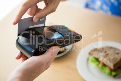 Hand holding a credit card next to the digital tablet in the cof