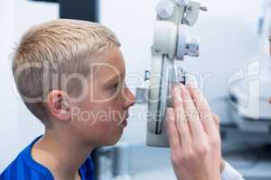 Young patient under going eye test through phoropter