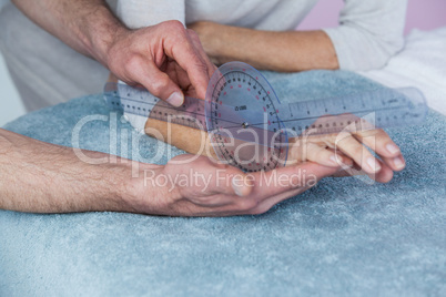 Physiotherapist measuring patient hand with goniometer