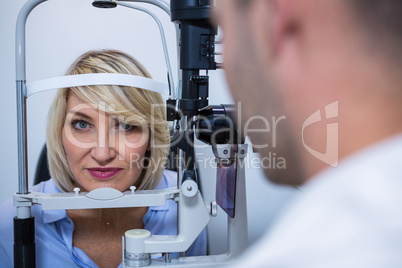 Optometrist examining female patient on slit lamp