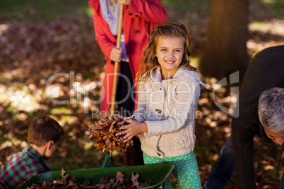 Girl picking up autumn leaves with family