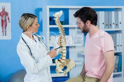 Physiotherapist explaining the spine model to patient