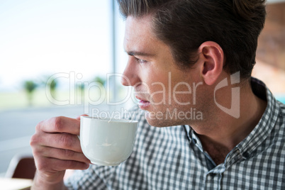 Thoughtful man looking out of the window while having coffee