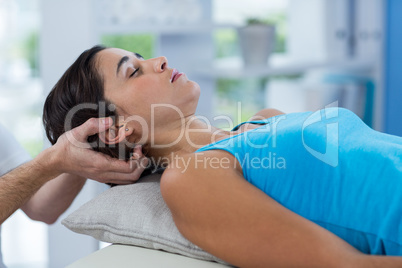 Male physiotherapist giving head massage to female patient