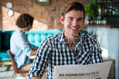 Portrait of smiling man reading a business newspaper