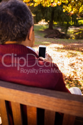 Man using cellphone while relaxing on bench