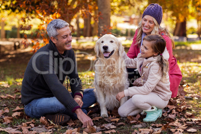 Happy family sitting with dog at park