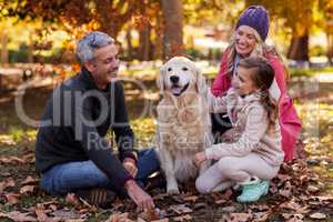 Happy family sitting with dog at park