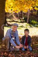 Portrait of grandfather and grandson playing with autumn leaves