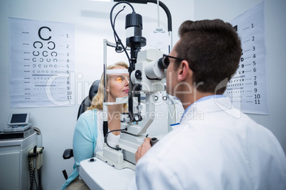 Optometrist examining female patient on slit lamp