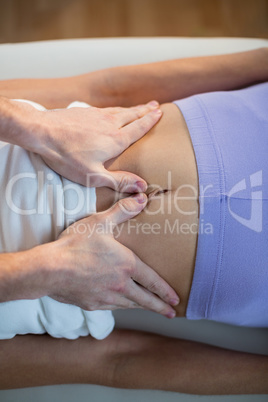 Male physiotherapist giving stomach massage to female patient