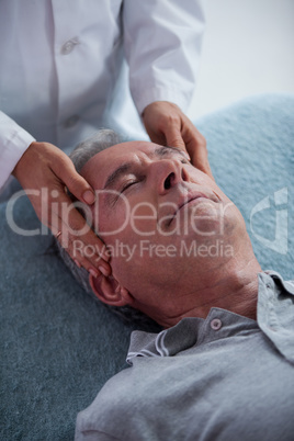 Senior man receiving head massage from physiotherapist