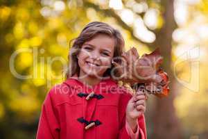 Smiling girl holding autumn leaves at park