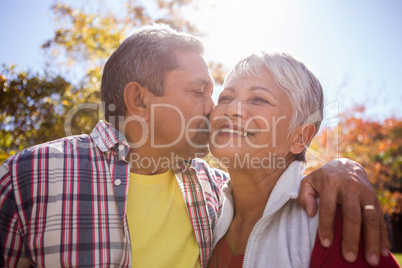 An elderly man kissing his wife