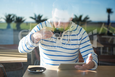 Man using digital tablet while having coffee