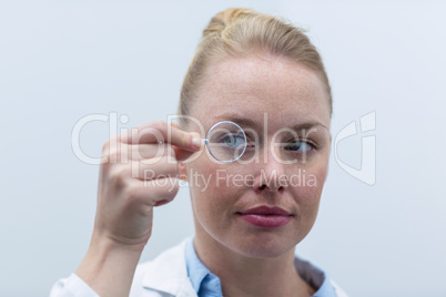 Female optometrist looking through magnifying glass