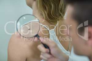 Dermatologist examining mole with magnifying glass
