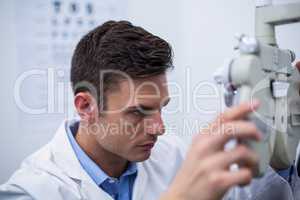 Attentive optometrist looking through phoropter