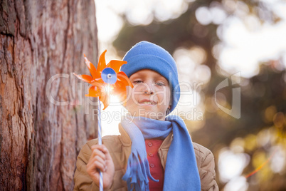 Low angle portrait of smiling boy holding pinwheel at park