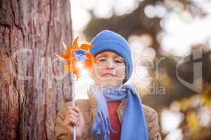 Low angle portrait of smiling boy holding pinwheel at park