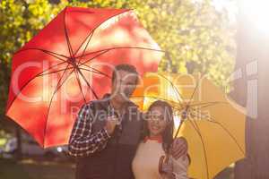 Portrait of couple holding umbrellas