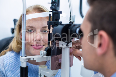 Optometrist examining female patient on slit lamp