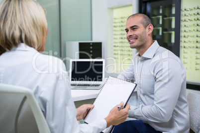 Female optometrist talking to male patient