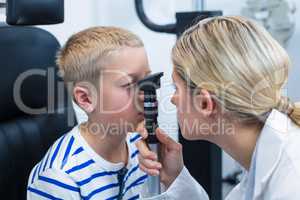 Female optometrist examining young patient with ophthalmoscope