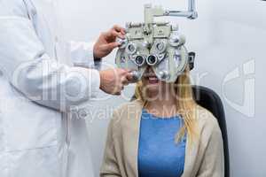 Optometrist examining female patient on phoropter