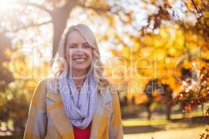 Portrait of smiling woman against trees at park