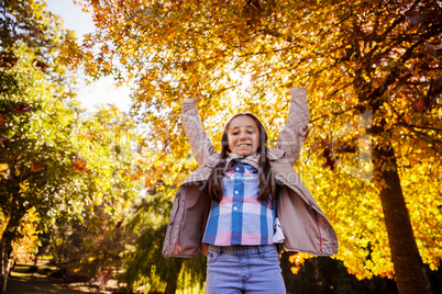 Low angle portrait of smiling girl with arms raised while standi