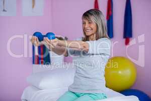 Smiling senior woman holding dumbbell