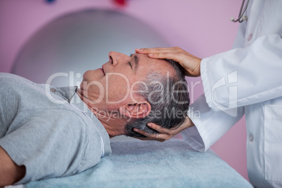 Senior man receiving head massage from physiotherapist