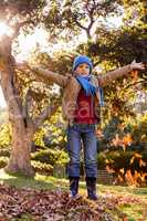 Portrait of boy with arms outstretched at park during autumn