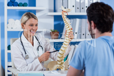 Physiotherapist explaining the spine model to patient