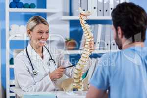 Physiotherapist explaining the spine model to patient