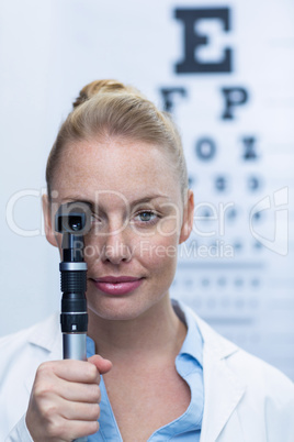 Female optometrist looking through ophthalmoscope