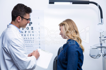 Optometrist discussing eye test report with female patient