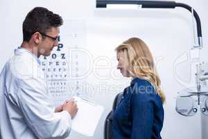 Optometrist discussing eye test report with female patient