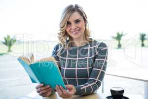 Woman reading novel in cafeteria