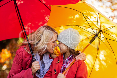 Cheerful mother and daughter with umbrella at park