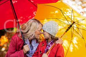 Cheerful mother and daughter with umbrella at park