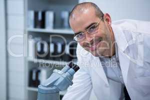 Smiling male optometrist with microscope