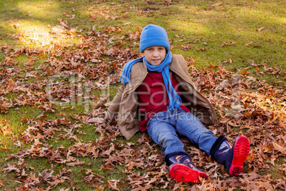 Portrait of boy sitting at park during autumn