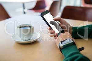 Hand using mobile phone with cup of coffee in table