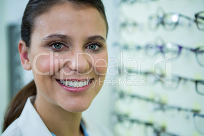 Optometrist in spectacles smiling in optical store