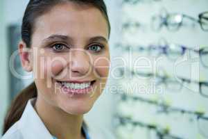 Optometrist in spectacles smiling in optical store